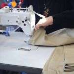 Efficient sewing of work uniforms on industrial sewing machine at TopLine Uniforms.